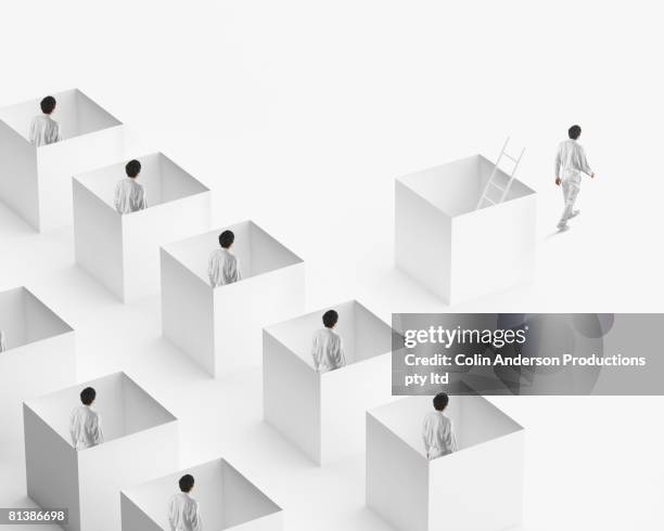 european businessman walking away from businessmen in boxes - herhaling begrippen stockfoto's en -beelden