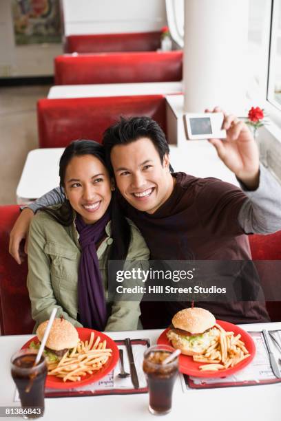 asian couple taking own photograph - waitress booth stock pictures, royalty-free photos & images