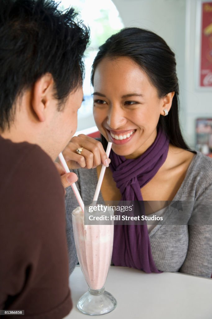 Asian couple sharing milkshake