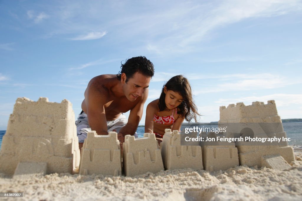 Hispanic father and daughter building sand castle