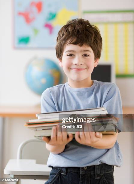 hispanic boy holding stack of school books - fachbuch stock-fotos und bilder