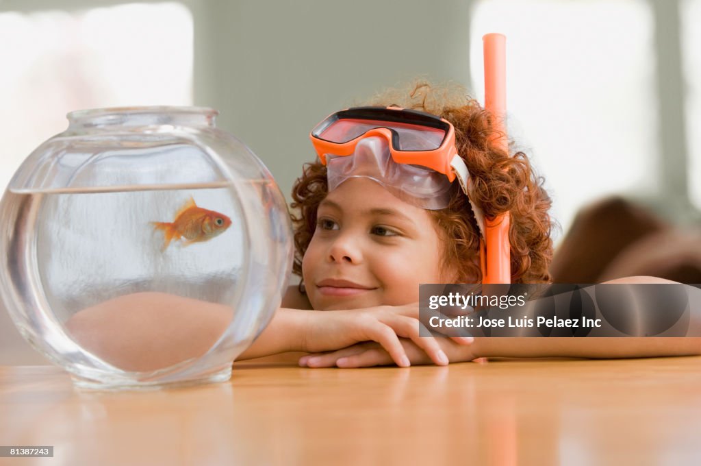 Mixed Race boy looking at fish in bowl