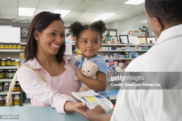african mother and daughter getting prescription at pharmacy - black pharmacist stock pictures, royalty-free photos & images