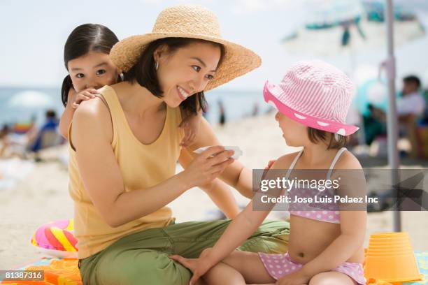 asian mother applying sunscreen to daughter - applying sunscreen stock pictures, royalty-free photos & images