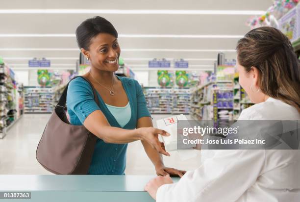 african woman picking up prescription at pharmacy - black pharmacist stock pictures, royalty-free photos & images