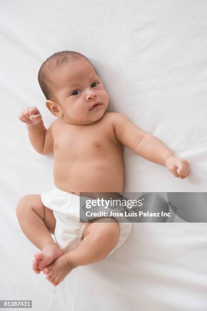 hispanic baby laying on bed - ein weibliches baby allein stock-fotos und bilder