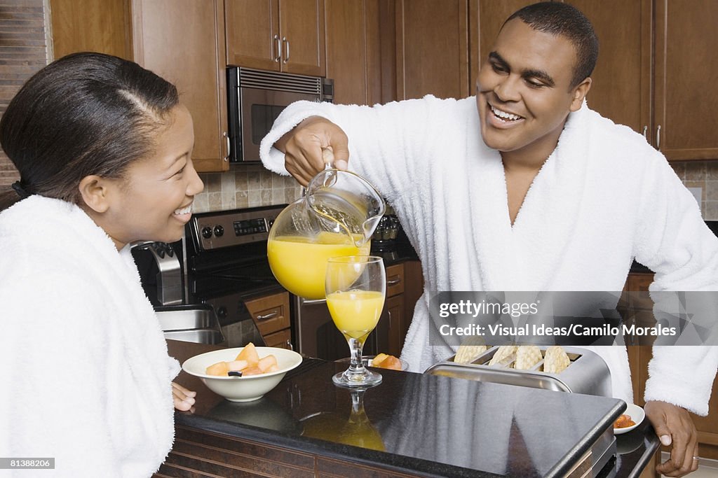 African man pouring orange juice for wife