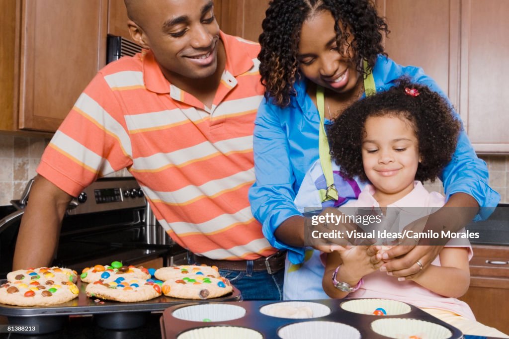 African parents and daughter making cupcakes
