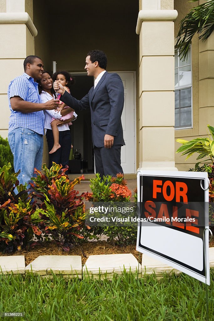 Hispanic real estate agent giving house keys to African family
