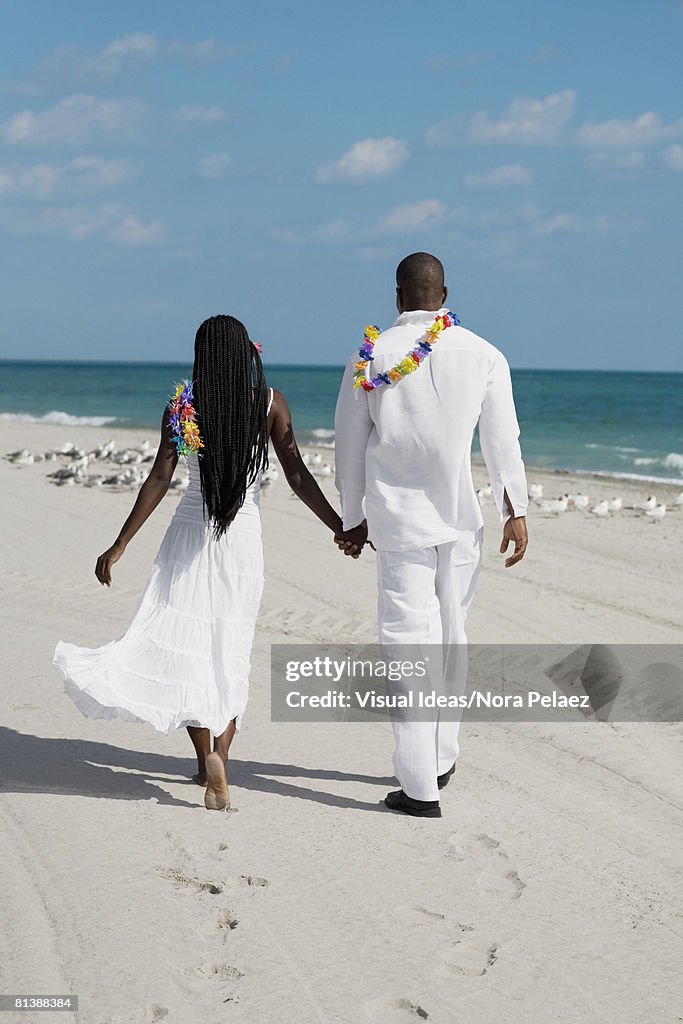 African couple holding hands at beach