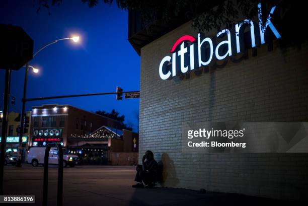 Pedestrian sits on front of a Citigroup Inc. Bank branch at dusk in Chicago, Illinois, U.S., on Wednesday, July 12, 2017. Citigroup Inc. Is scheduled...