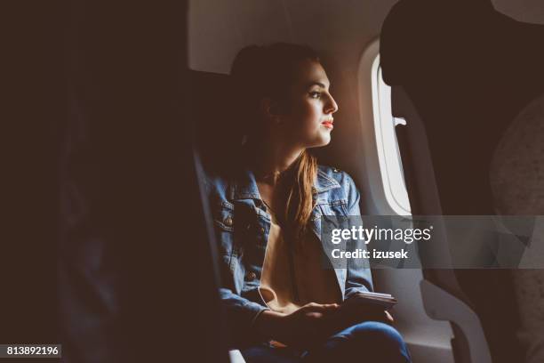 vrouwelijke passagier op zoek buiten vliegtuig raam - window seat stockfoto's en -beelden