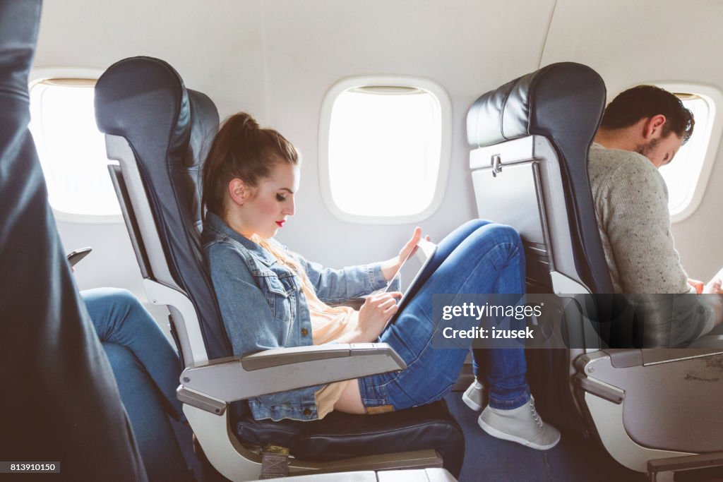 Female passenger using tablet pc during flight