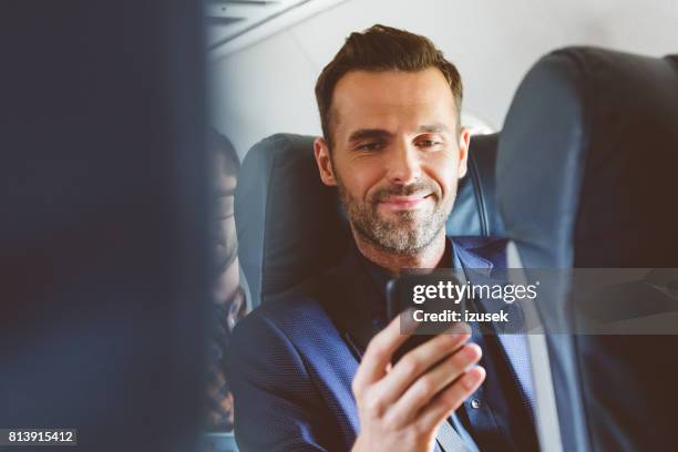 hombre viaja en avión y usar teléfono móvil - aircraft wifi fotografías e imágenes de stock