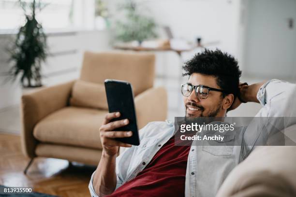 smiling man with one hand behind his head is enjoying his day off. - play off stock pictures, royalty-free photos & images