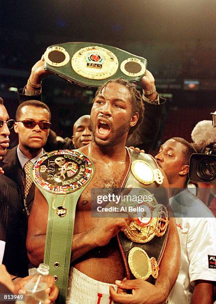 Lennox Lewis celebrates with all three championship belts after winning the World Heavyweight Championship unification fight against Evander...