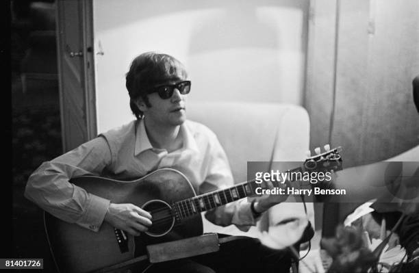 John Lennon of the Beatles plays the guitar in a hotel room in Paris, 16th January 1964.