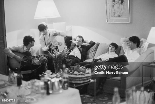 The Beatles relax in a hotel room in Paris, 16th January 1964. From left to right, John Lennon , George Harrison , band manager Brian Epstein , Ringo...