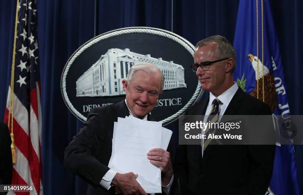 Attorney General Jeff Sessions picks up his remarks as Acting FBI Director Andrew McCabe looks on during a news conference to announce significant...