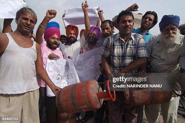 Indian protesters hold placards and cooking gas LPG cylinders during a protest against the government increase in the price of petrol, diesel and...