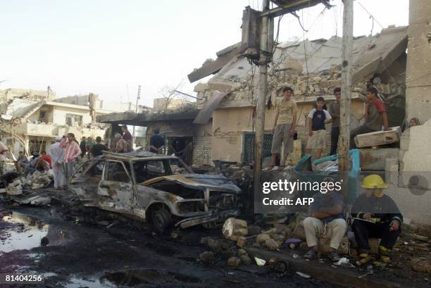 Fire men and residents look at the damage following a suicide bombing in the Al-Shab neighbourhood of Baghdad on June 4, 2008. A suicide bomber in a...