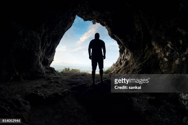 silhouette of a male person at the cave entrance - cave stock pictures, royalty-free photos & images