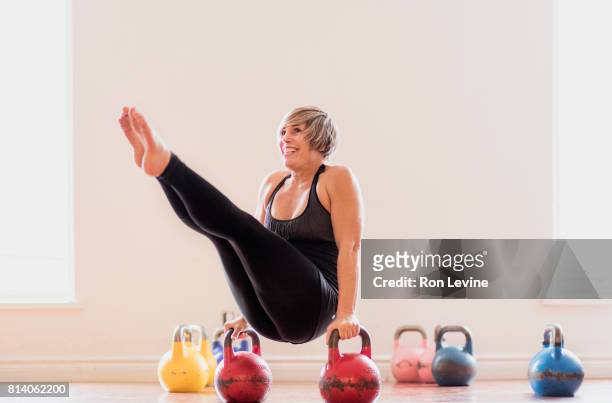 mature woman balancing between two kettlebells - kettlebell - fotografias e filmes do acervo