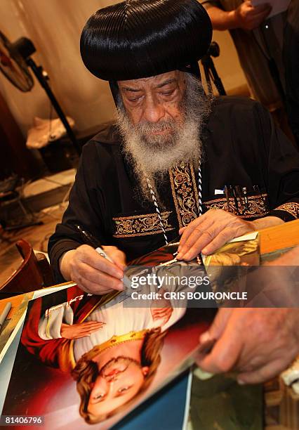 Pope Shenouda III, the 84-year-old head of the Coptic Orthodox Church, Patriarch of Alexandria and the See of St. Mark, signs posters of Jesus...