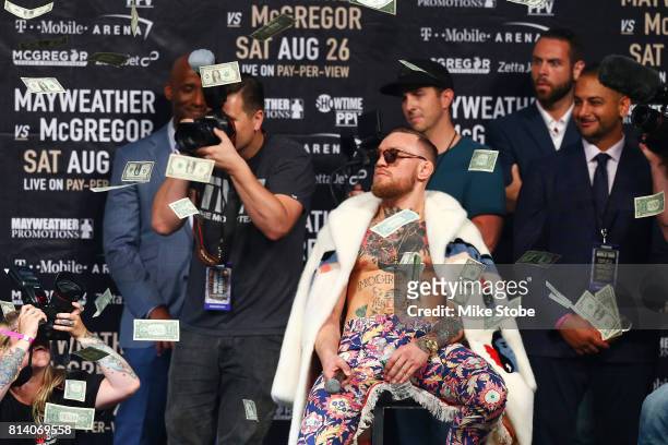 Conor McGregor looks on as money rains down during the Floyd Mayweather Jr. V Conor McGregor World Press Tour event at Barclays Center on July 13,...
