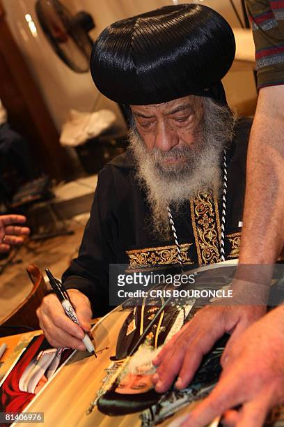 Pope Shenouda III, the 84-year-old head of the Coptic Orthodox Church, Patriarch of Alexandria and the See of St. Mark, signs posters of himself to...