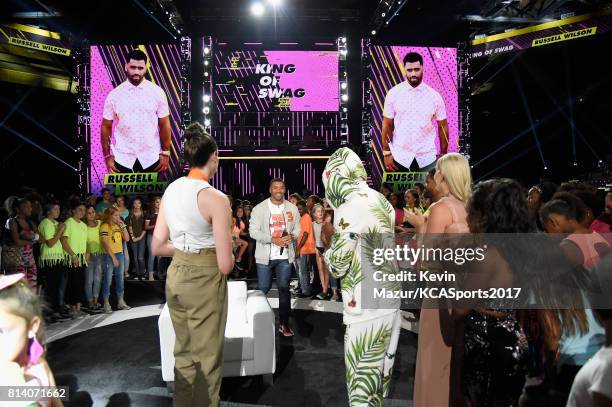 Host Russell Wilson accepts the King of Swag award from WNBA player Breanna Stewart, TV personality Nick Cannon, World Cup skiier Lindsey Vonn, and...
