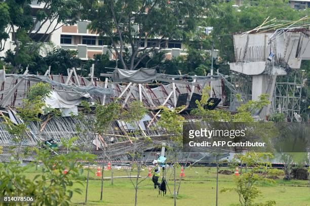 Land Transport Authority inspector walks past the area where an under-construction elevated highway collapsed in Singapore on July 14, 2017. One...