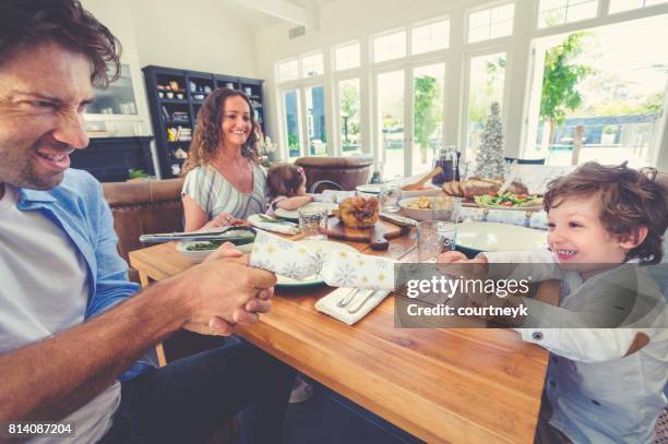 father and son pulling a christmas cracker. - christmas crackers stock pictures, royalty-free photos & images