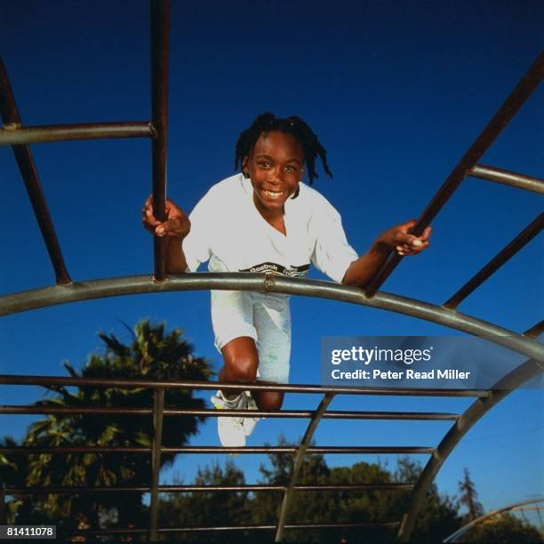 Tennis: Portrait of 10-year-old Venus Williams on monkey bars in playground, Compton, CA 5/6/1991