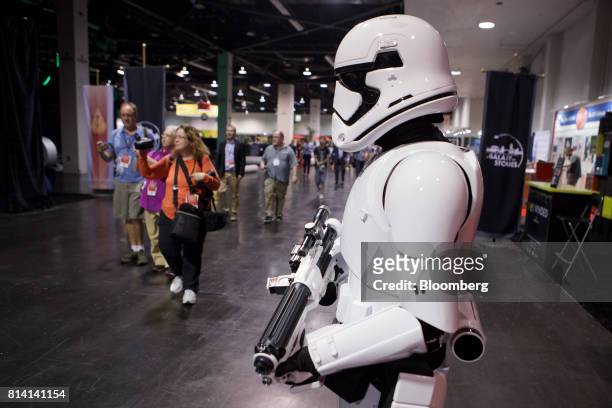 Attendees walk past a person dressed as a Stormtrooper during the unveiling of the Walt Disney Co. "Star Wars" lands 3-D model ahead of the D23 Expo...
