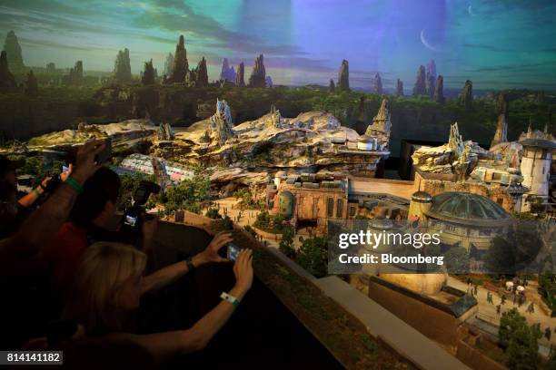 Attendees take photographs of the Walt Disney Co. "Star Wars" lands 3-D model unveiled ahead of the D23 Expo in Anaheim, California, U.S., on...