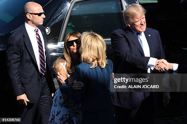 President Donald Trump shakes hands as he steps out of the US presidential state car called "The Beast" as US First Lady Melania Trump kisses...