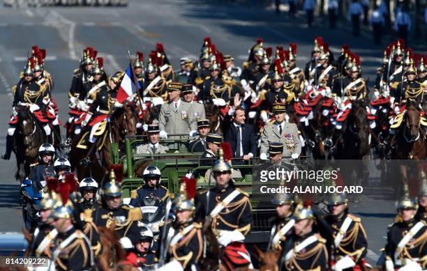 French President Emmanuel Macron waves next to Chief of the Defence Staff of the French Army General Pierre de Villiers as they stand in a military...