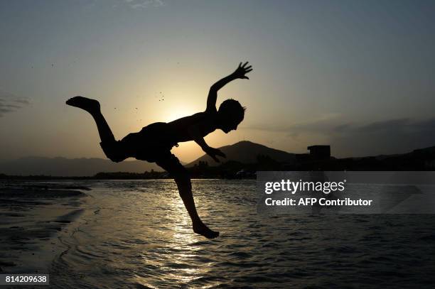 In this photograph taken on July 13 an Afghan youth jumps into a river on the outskirts of Jalalabad. / AFP PHOTO / NOORULLAH SHIRZADA