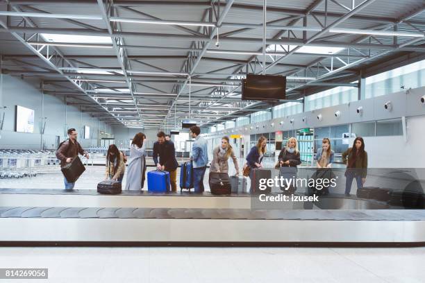 passengers collecting baggage from luggage conveyor belt at airport - baggage claim imagens e fotografias de stock