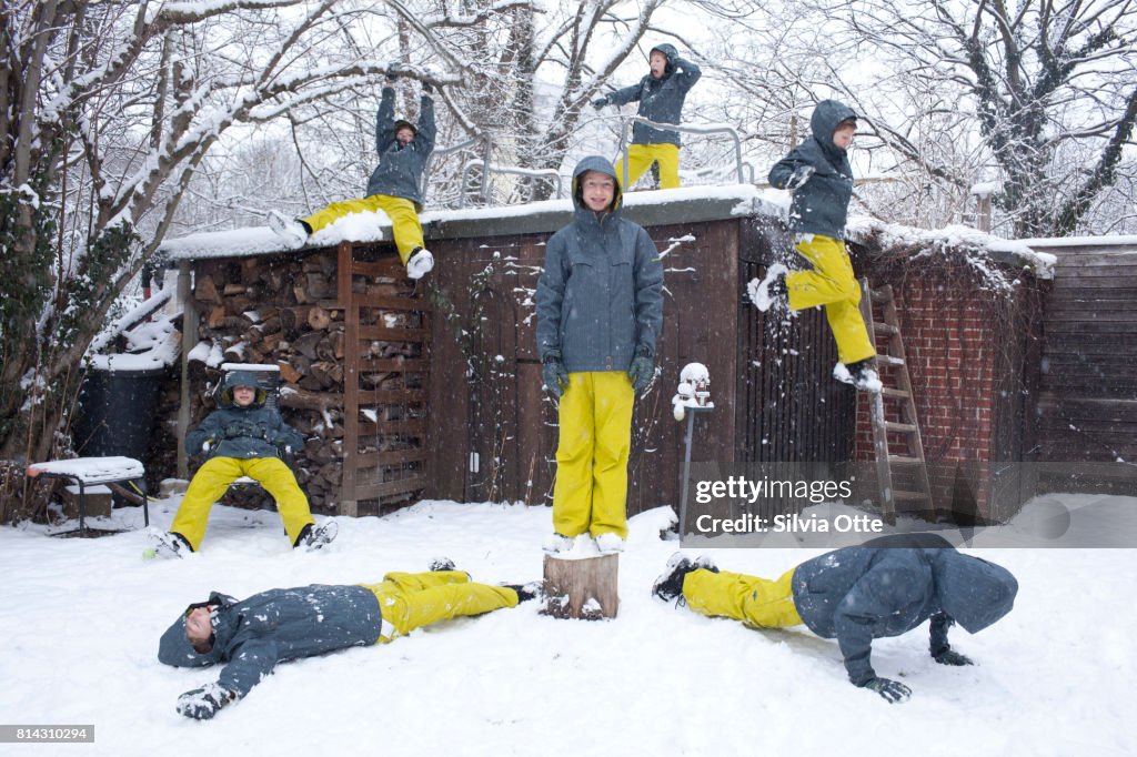 Boy standing in snowy garden surrounded by look-alikes of himself