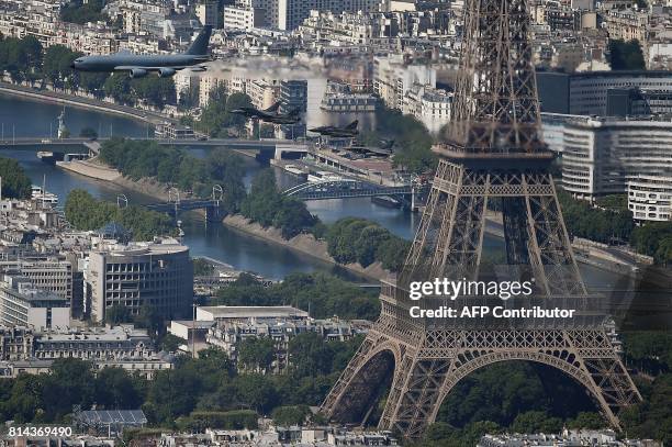 An aerial view shows a Boeing C135 refueling tanker followed by two Rafale B fighter aircrafts and two Mirage 2000N jets flying past the Eiffel Tower...