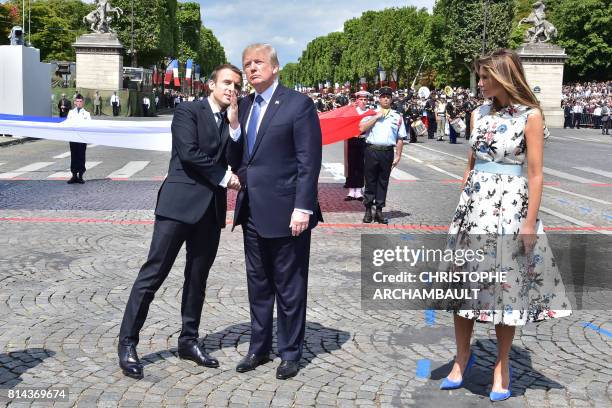 French President Emmanuel Macron shakes hands with US President Donald Trump, next to US First Lady Melania Trump, during the annual Bastille Day...