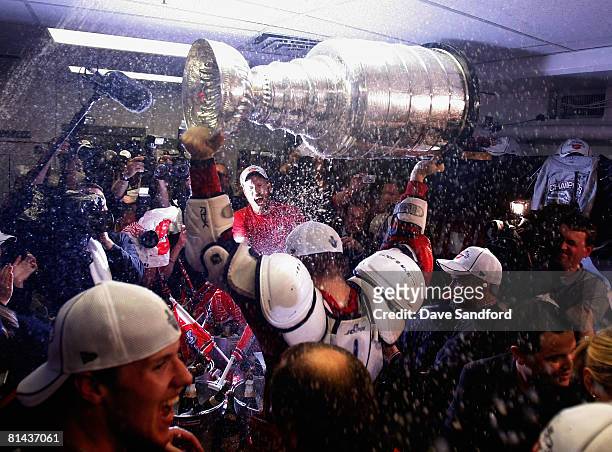 Johan Franzen of the Detroit Red Wings sprays teammates with champagne as they celebrate with the Stanley Cup in the locker room after defeating the...