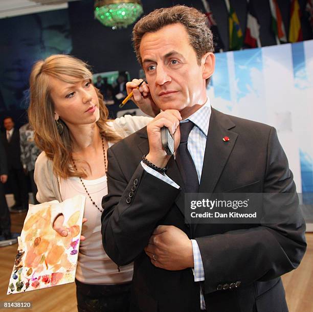 In this photo illustration studio artist Claire Galvin poses with a new waxwork figure of French President Nicolas Sarkozy at Madame Tussauds on June...