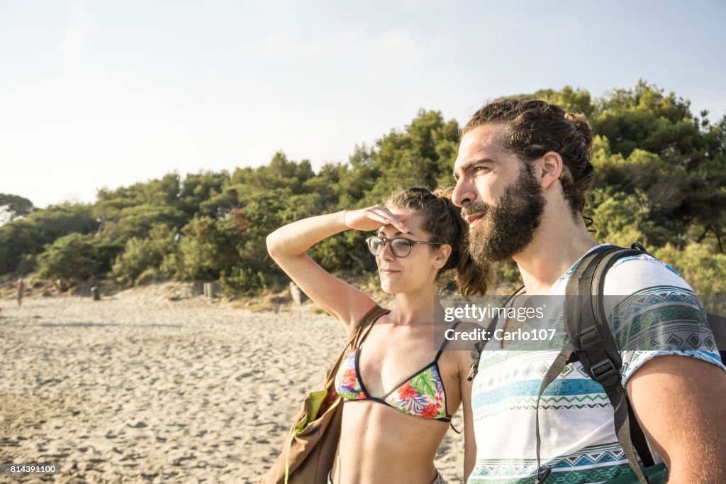 Giovane coppia che guarda l'orizzonte su una spiaggia in Toscana