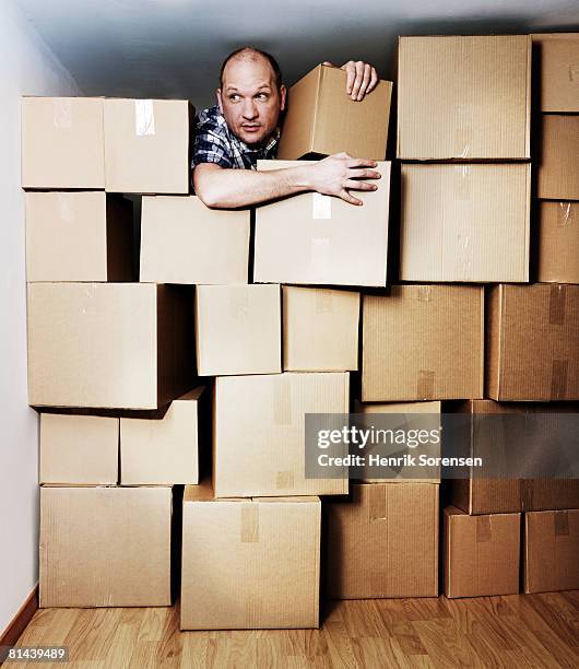 man looking out from a room filled with boxes - stuck indoors stock pictures, royalty-free photos & images