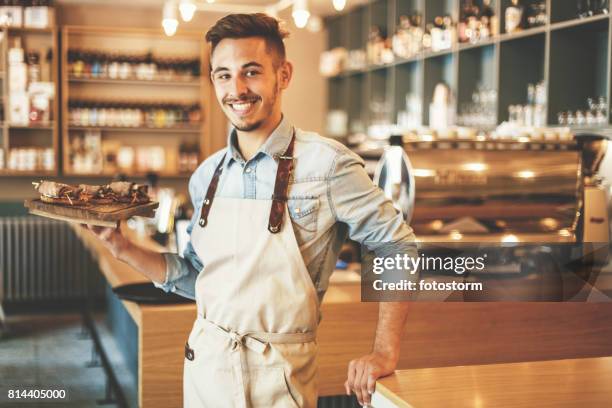 manliga servitör hålla facket och leende - servitör bildbanksfoton och bilder