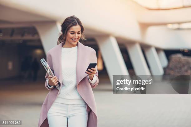 modische frau mit smartphone - elegante kleidung stock-fotos und bilder
