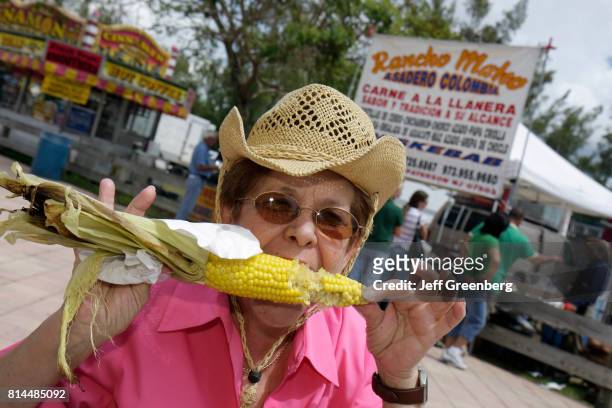 Senior woman eating a roasted corn on the cob at the Miami International Agriculture and Cattle Show.